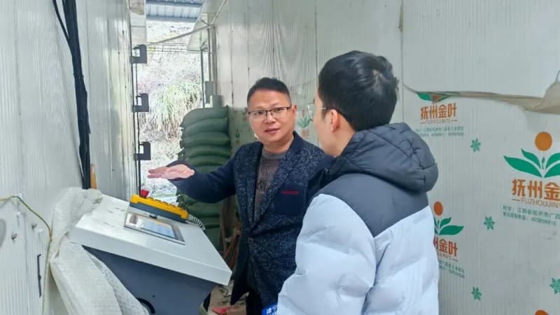 Jason demonstrating the operation of the automated tobacco leaf loading machine for curing barns to reporters